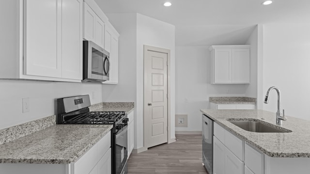kitchen featuring stainless steel appliances, a sink, recessed lighting, and white cabinetry