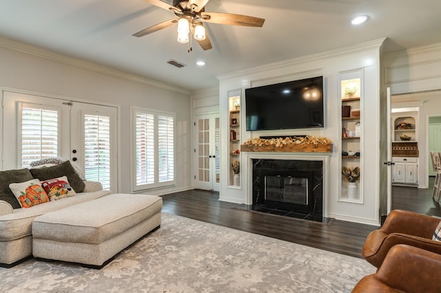 living room with a fireplace, ceiling fan, crown molding, dark wood-type flooring, and french doors