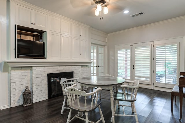 dining space with ceiling fan, ornamental molding, a fireplace, and dark hardwood / wood-style flooring