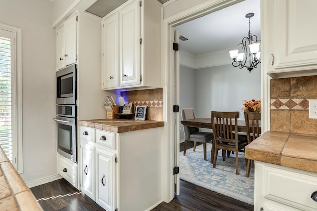 kitchen featuring pendant lighting, appliances with stainless steel finishes, white cabinetry, tasteful backsplash, and dark hardwood / wood-style flooring