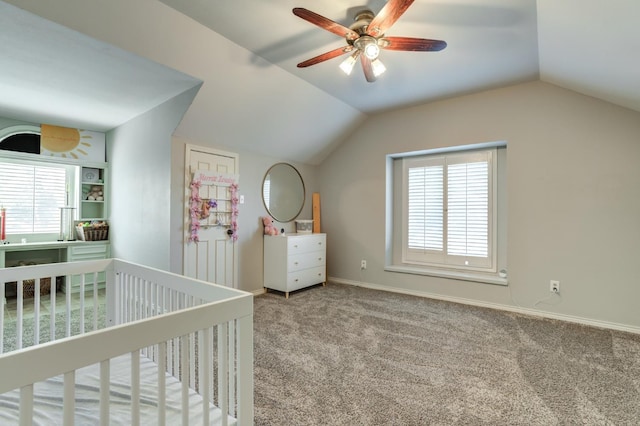 unfurnished bedroom with a crib, vaulted ceiling, ceiling fan, and carpet