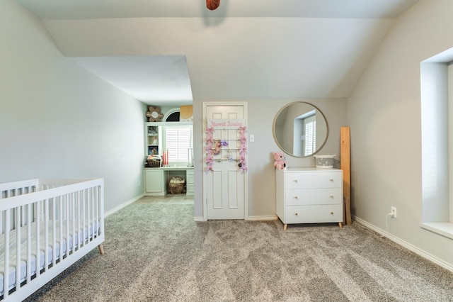 unfurnished bedroom with a crib, light colored carpet, and vaulted ceiling