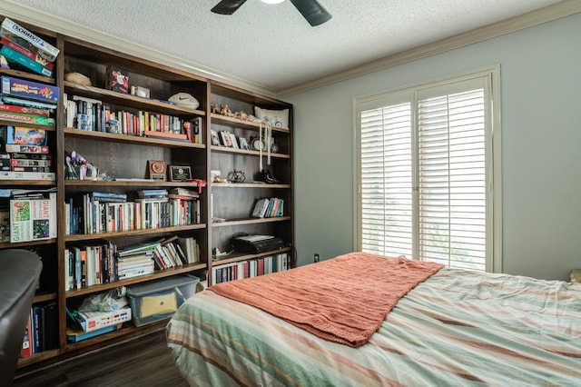 bedroom featuring dark wood-type flooring, ceiling fan, ornamental molding, and a textured ceiling