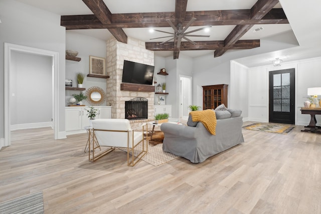 living room featuring beamed ceiling, coffered ceiling, a fireplace, and light hardwood / wood-style floors