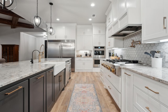 kitchen with white cabinetry, hanging light fixtures, stainless steel appliances, and custom range hood