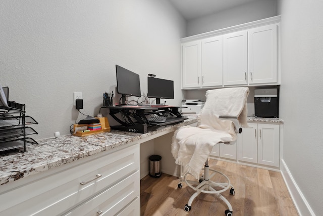 office space with built in desk and light hardwood / wood-style flooring