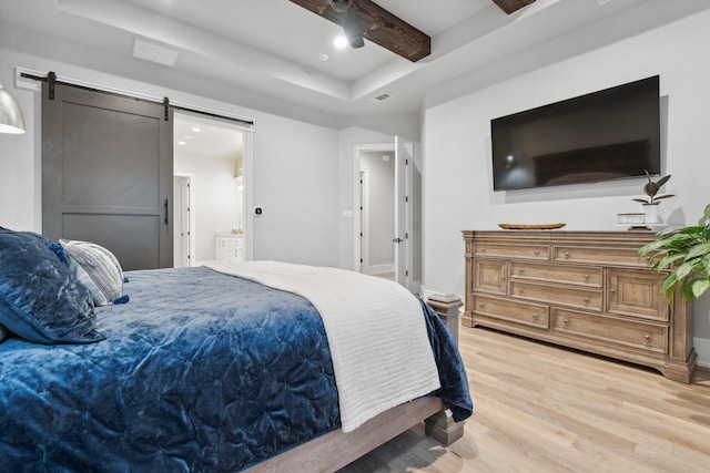 bedroom featuring ceiling fan, hardwood / wood-style floors, a raised ceiling, a barn door, and beamed ceiling