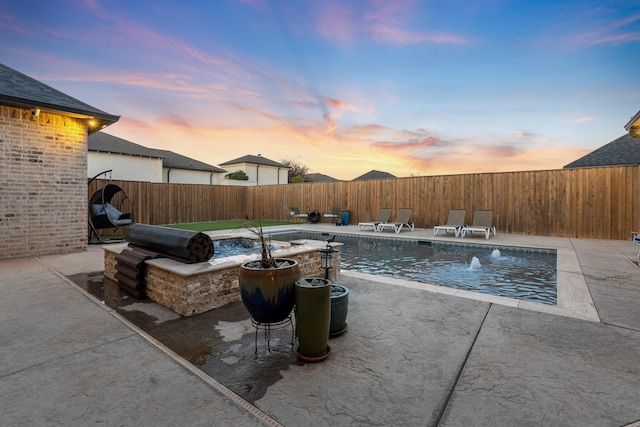 pool at dusk featuring a patio and pool water feature