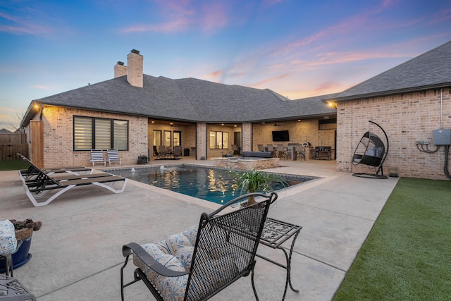 pool at dusk with exterior bar and a patio area