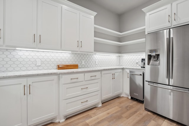 kitchen featuring tasteful backsplash, white cabinets, stainless steel fridge with ice dispenser, light stone countertops, and light hardwood / wood-style flooring