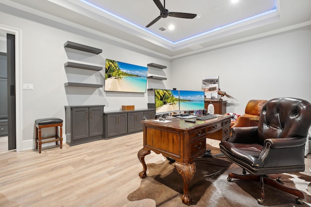 office area with light hardwood / wood-style flooring, ornamental molding, a raised ceiling, and ceiling fan