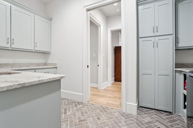 kitchen featuring gray cabinets, sink, and light stone counters