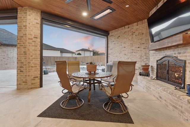 dining room with an outdoor brick fireplace, brick wall, plenty of natural light, and wooden ceiling