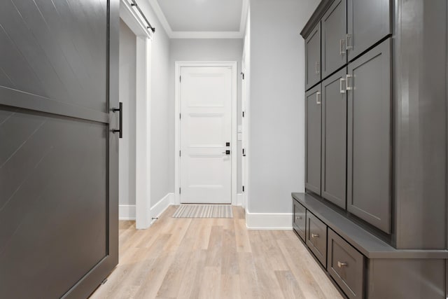 mudroom featuring crown molding, a barn door, and light hardwood / wood-style flooring