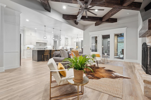 living room with coffered ceiling, beam ceiling, ceiling fan with notable chandelier, and light wood-type flooring