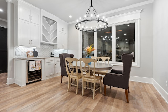 dining space featuring wine cooler, ornamental molding, and light hardwood / wood-style floors