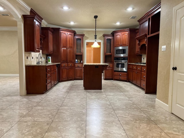 kitchen with sink, light stone counters, crown molding, a center island, and appliances with stainless steel finishes