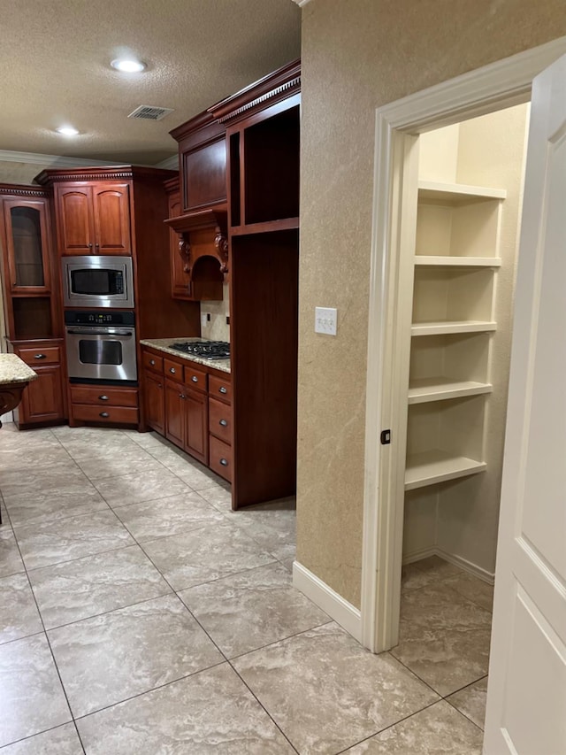 kitchen featuring stainless steel appliances, ornamental molding, light stone countertops, and a textured ceiling