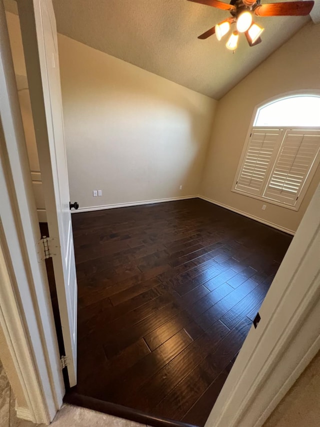 empty room featuring lofted ceiling, dark wood-type flooring, a textured ceiling, and ceiling fan