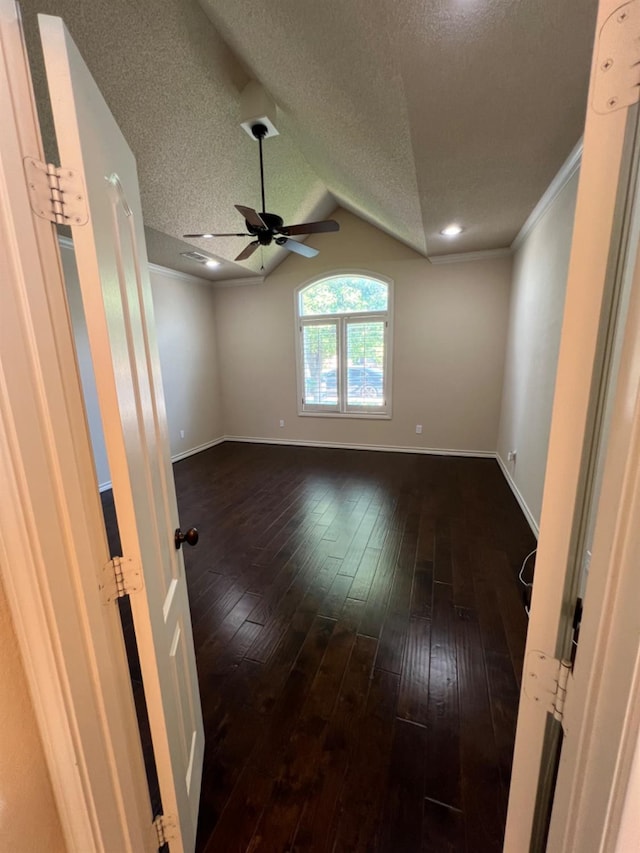 empty room featuring lofted ceiling, dark hardwood / wood-style floors, and a textured ceiling