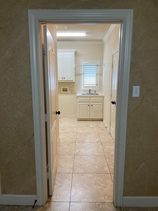 hall featuring ornamental molding, sink, and light tile patterned floors