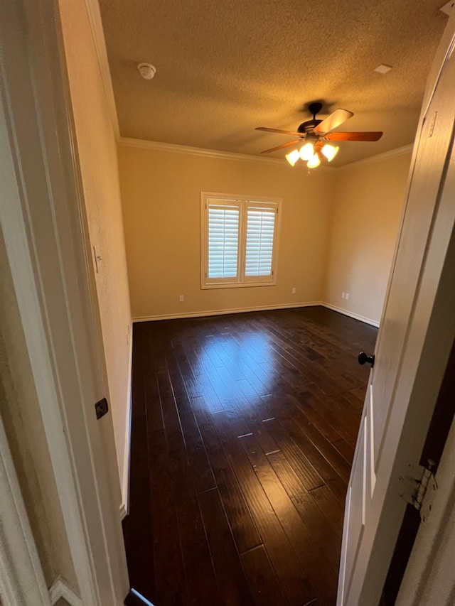 empty room with ornamental molding, dark hardwood / wood-style floors, a textured ceiling, and ceiling fan