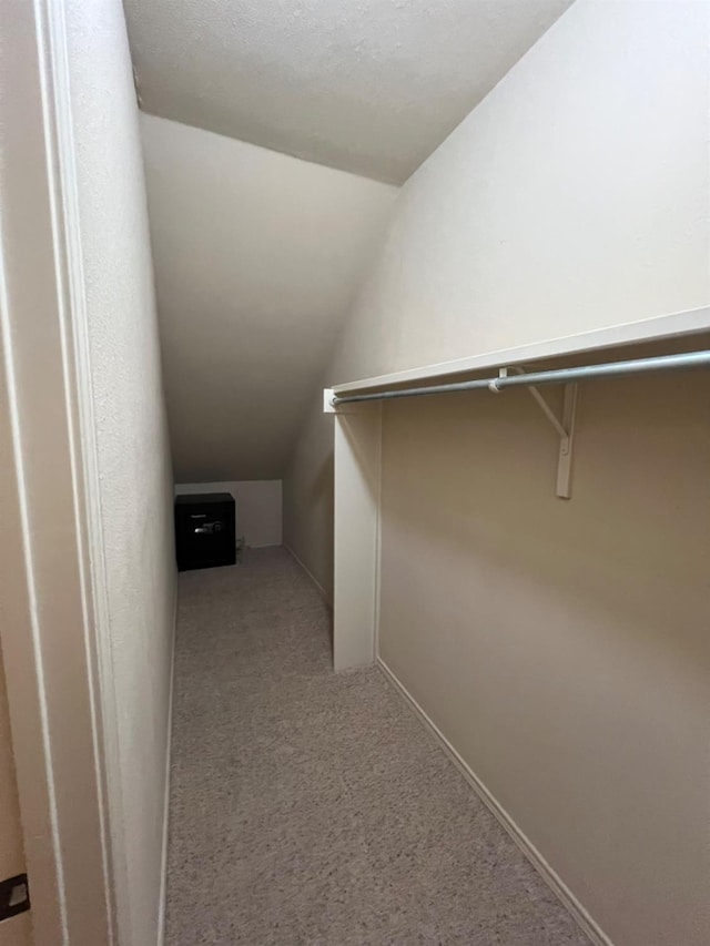 walk in closet featuring light colored carpet and vaulted ceiling