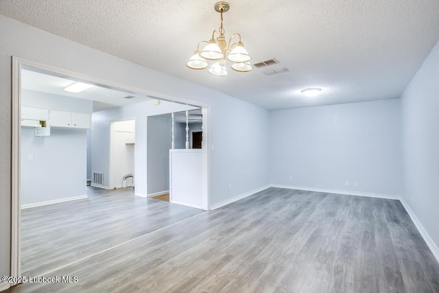 504 53rd St, Lubbock, TX 79404 - empty room with light wood finished floors, a chandelier, and a textured ceiling