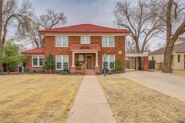 view of front of house with a carport, brick siding, a front yard, and central AC