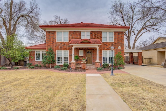 view of front of house with brick siding, concrete driveway, a tile roof, and a front yard