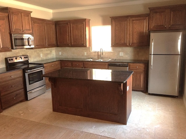 kitchen with sink, crown molding, appliances with stainless steel finishes, a kitchen island, and backsplash