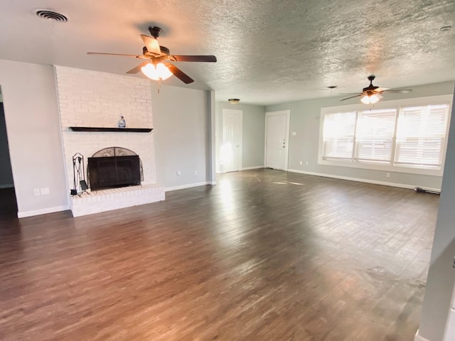 unfurnished living room featuring a brick fireplace, dark hardwood / wood-style floors, a textured ceiling, and ceiling fan