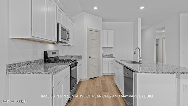 426 14th St, Wolfforth, TX 79382 - kitchen with stainless steel appliances, light wood finished floors, a kitchen island with sink, white cabinetry, and light stone counters