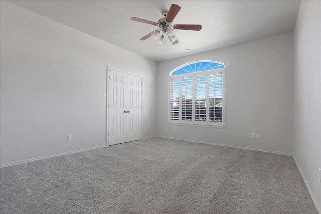 carpeted spare room featuring ceiling fan