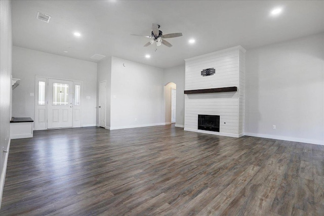 unfurnished living room featuring ceiling fan, a large fireplace, and dark hardwood / wood-style flooring