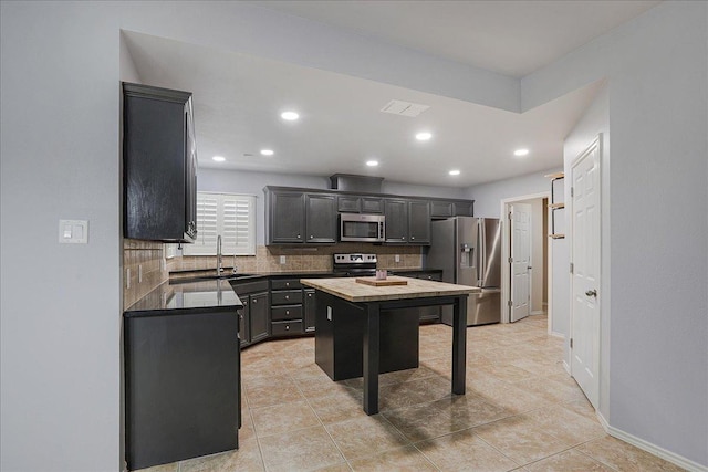 kitchen with sink, tasteful backsplash, light tile patterned floors, a kitchen island, and stainless steel appliances