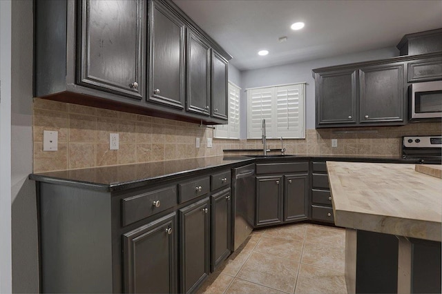 kitchen with sink, wooden counters, light tile patterned floors, stainless steel appliances, and backsplash