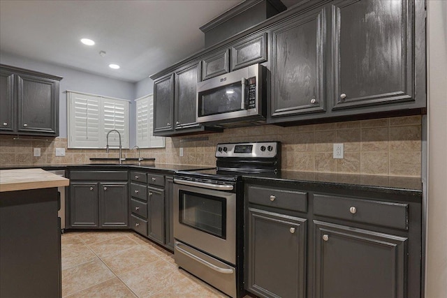 kitchen with tasteful backsplash, sink, light tile patterned floors, and stainless steel appliances