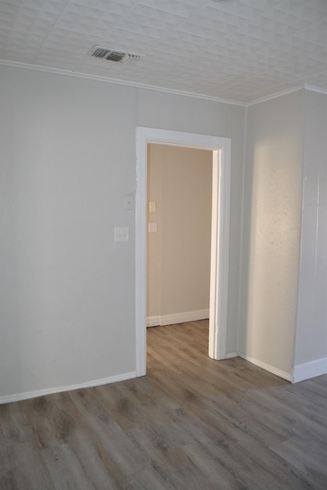 spare room featuring crown molding and hardwood / wood-style flooring