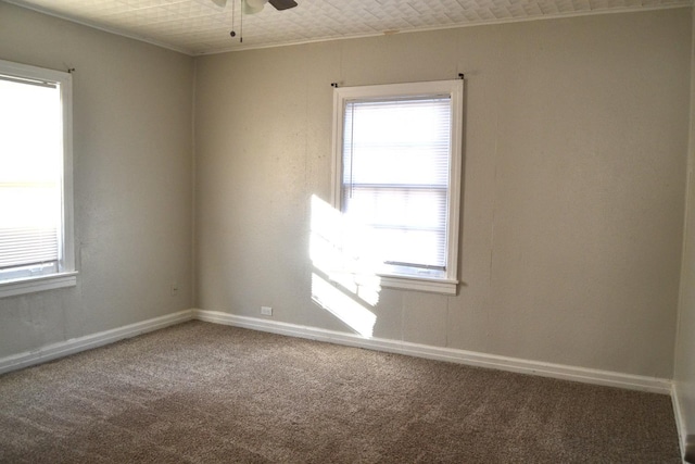 carpeted spare room with ceiling fan, crown molding, and a healthy amount of sunlight