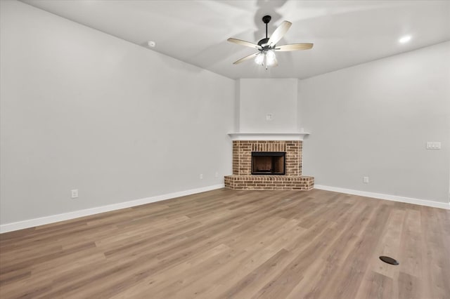 unfurnished living room with ceiling fan, a fireplace, and light hardwood / wood-style flooring