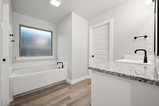 bathroom with vanity, wood-type flooring, and a tub