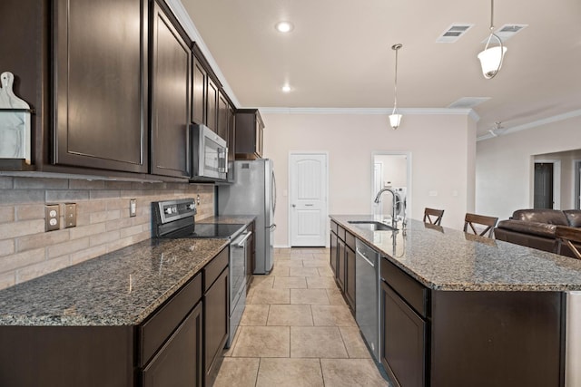 kitchen featuring sink, stainless steel appliances, hanging light fixtures, and dark stone counters