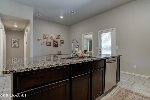7511 31st St, Lubbock, TX 79407 - kitchen featuring dishwasher, light tile patterned floors, dark brown cabinets, light stone countertops, and a center island with sink