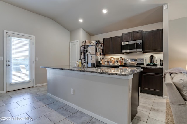 7511 31st St, Lubbock, TX 79407 - kitchen with stainless steel appliances, dark stone counters, dark brown cabinetry, lofted ceiling, and an island with sink