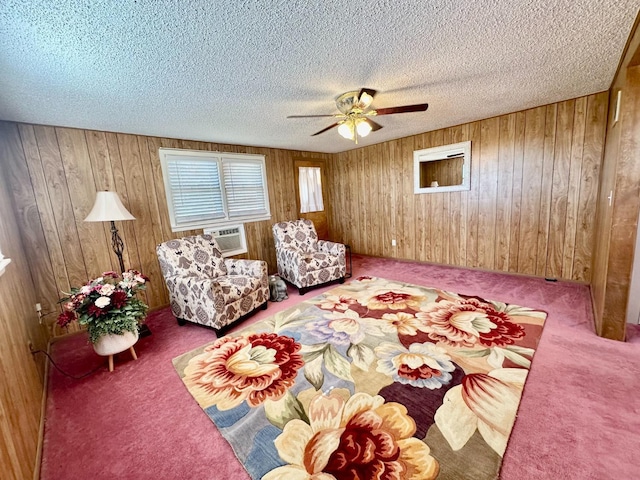 living room with wooden walls, carpet floors, a wall mounted AC, ceiling fan, and a textured ceiling