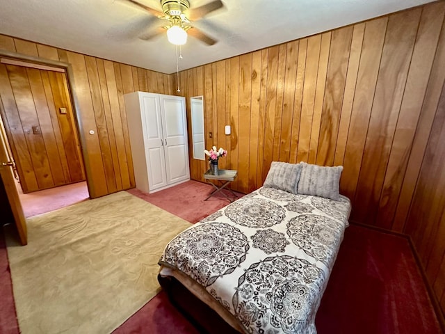 carpeted bedroom featuring ceiling fan and wood walls