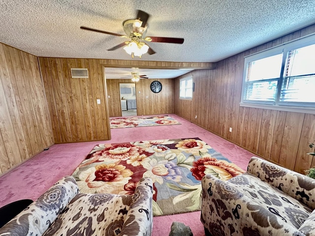 bedroom with ceiling fan, carpet floors, a textured ceiling, and wood walls