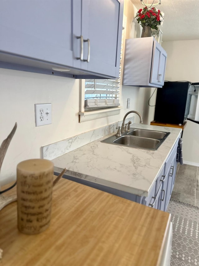 kitchen featuring sink, a textured ceiling, and light stone counters