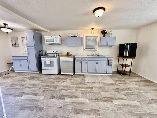 kitchen featuring white appliances, sink, a textured ceiling, and gray cabinetry